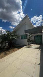 a white house with a palm tree in front of it at Casa com Piscina em Maringá in Maringá