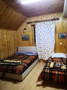 two beds in a room with wooden walls and wooden floors at Mountain Lodge - Mavrovo in Mavrovo