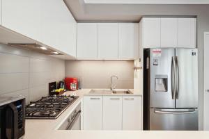 a kitchen with white cabinets and a stainless steel refrigerator at Tranquil Gumnut Cottage - Close to Airport in Perth