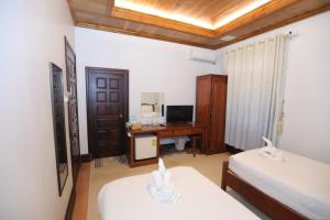 een kamer met 2 bedden en een bureau met een computer bij Villa KiengKham晶康民宿 in Luang Prabang