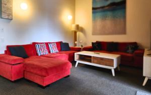 een woonkamer met twee rode banken en een salontafel bij Fraser Island - Holiday Heaven in Fraser Island