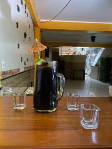 uma bebida num frasco com dois copos na mesa em Hotel EL BRAVO em Carhuaz