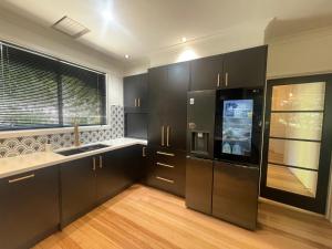 duża kuchnia z czarnymi szafkami i oknem w obiekcie No 4 Yarra Valley Events Accommodation 6 Adults w mieście Healesville