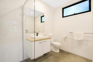 Un baño blanco con inodoro y lavabo. en Delany by the Park - House, en Bright