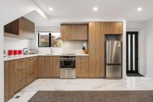 a kitchen with wooden cabinets and stainless steel appliances at Light & Spacious 2Bdrm Townhouse Off Street Park in Christchurch