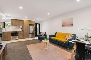 a living room with a blue couch and a kitchen at Light & Spacious 2Bdrm Townhouse Off Street Park in Christchurch