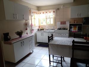 eine Küche mit weißen Schränken und einem Tisch darin in der Unterkunft Férias!! Inspire-se e Renove! 7km centroMar Torres RS in Torres