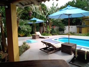 einen Pool mit 2 Sonnenschirmen und Liegestühlen neben einem Pool in der Unterkunft Férias!! Inspire-se e Renove! 7km centroMar Torres RS in Torres