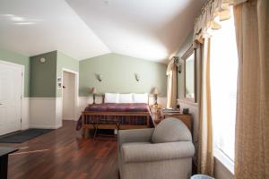 1 dormitorio con 1 cama, 1 silla y 1 sofá en Swift River Suites, en Rumford