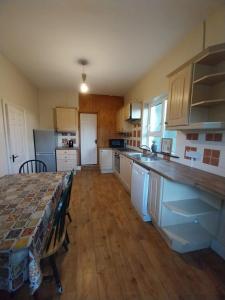 a kitchen with white cabinets and a table in it at Rosie's cottage in Gweedore