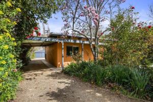 a small yellow house with a tree and some bushes at Roses on the River - An absolute river frontage cottage in Bright