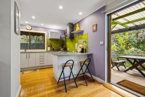 a kitchen with a counter and two bar stools at Roses on the River - An absolute river frontage cottage in Bright