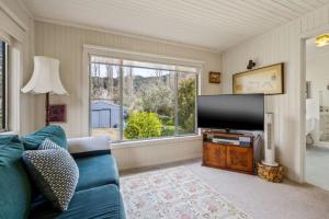 a living room with a blue couch and a flat screen tv at Roses on the River - An absolute river frontage cottage in Bright