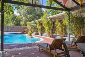 a swimming pool with two chairs next to a house at Haven Studio Hideaway near Airport in Perth