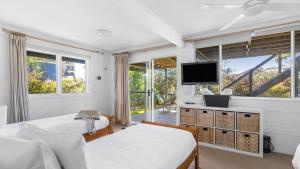 a bedroom with two beds and a flat screen tv at Mollymook Breeze in Narrawallee