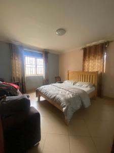 a bedroom with a bed and a chair and a window at Pal central nest in Kampala