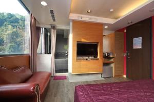 um quarto de hotel com um sofá e uma televisão em Yosemite Hot Spring Resort em Baihe