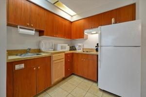 uma cozinha com armários de madeira e um frigorífico branco em I-DRIVE SUITES em Orlando