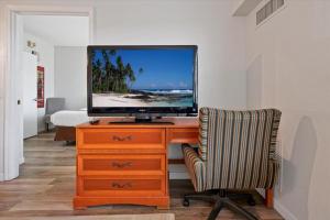 a television on a dresser with a chair and a desk at I-DRIVE SUITES in Orlando