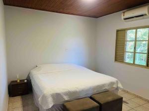 biała sypialnia z łóżkiem i oknem w obiekcie Chalé Rural - Haras Gabriela TC w mieście Nova Esperança