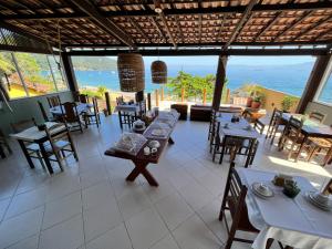 um restaurante com mesas e cadeiras e vista para o oceano em La Coquille em Praia de Araçatiba