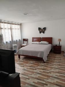 1 dormitorio con 1 cama con una mariposa en la pared en Casa de renta vacacional Andy-Cali -Valle del Cauca en Cali