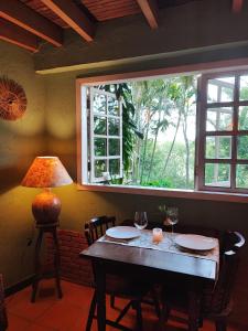 una mesa con dos vasos y una lámpara y una ventana en Champagny Pousada, en Santo Antônio do Pinhal