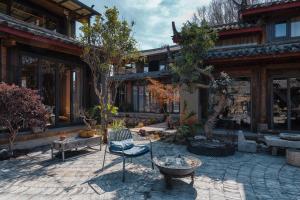 a building with a patio with chairs and trees at Qushe Snowy Mountain View Art B&B in Lijiang