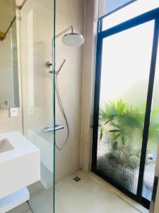 a bathroom with a shower and a glass door at Dori House in Gò Công