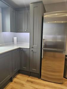 una cocina con nevera de acero inoxidable y armarios en Stunning 4 bed house en Rolleston