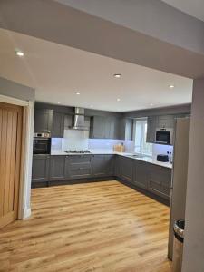 a large kitchen with gray cabinets and a wooden floor at Stunning 4 bed house in Rolleston