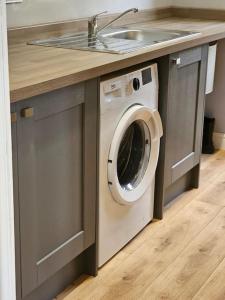 a washing machine under a sink in a kitchen at Stunning 4 bed house in Rolleston