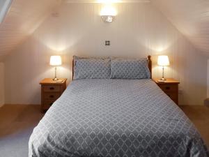 a bedroom with a bed with two lamps on tables at Sunnybank Cottage in Inveralligin