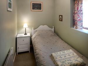 a small bedroom with a bed and a lamp at Panteg Cottage in Cross Inn