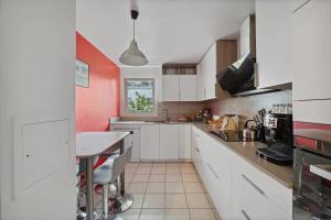 a kitchen with white cabinets and a table at Large bright T4 in Issy-les-Moulineaux - Welkeys in Issy-les-Moulineaux