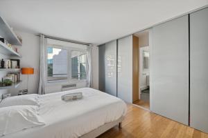 a bedroom with a white bed and a large window at Large bright T4 in Issy-les-Moulineaux - Welkeys in Issy-les-Moulineaux