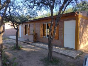 una pequeña casa de ladrillo con garaje blanco en Cabañas La Peperina 2 in 