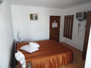 ein Schlafzimmer mit einem Bett mit zwei Kissen und einem TV in der Unterkunft Pensiune Restaurant Avangarde in Piteşti