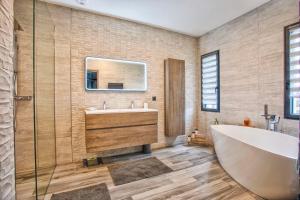 La salle de bains est pourvue d'une baignoire, d'un lavabo et d'un miroir. dans l'établissement Villa Howard — Jacuzzi, Tranquility & Parking, à Ranville