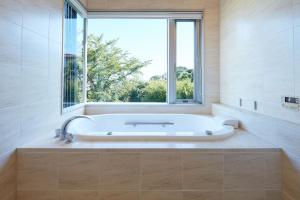 a bath tub in a bathroom with a window at Rembrandt Atsugi BETTEI サウナ&無煙ロースター付き12名定員 in Atsugi