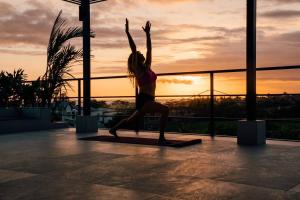 a woman doing a yoga pose in front of the sunset at Baliwood Villas - OCEAN VIEW 3BR in Canggu