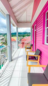 a pink house with benches on a balcony at La Flamboyant Hotel in Roseau