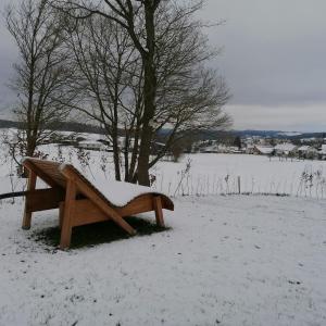 a wooden bench sitting in a snow covered field at Ferienhaus Knorreichenstieg in Nieder-Werbe