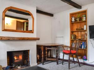 a living room with a fireplace and a table and a mirror at Cherry Cottage in Ipswich