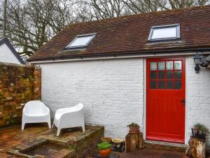 a white brick house with a red door and two white chairs at Uk46354 - Old Chimneys Cottage in Wivelsfield Green