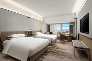 a hotel room with two beds and a flat screen tv at voco Changsha Airport, an IHG Hotel in Changsha