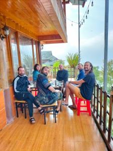 un grupo de personas sentadas en una mesa en un porche en Muong Hoa Hmong Homestay, en Sa Pa