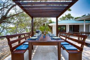 uma longa mesa de madeira com bancos azuis num pátio em Photo Perfect-Beachfront 2 Bedroom-Infinity Pool em Placencia Village
