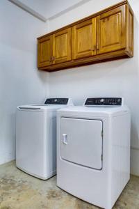 two washing machines in a kitchen with wooden cabinets at Photo Perfect-Beachfront 2 Bedroom-Infinity Pool in Placencia Village