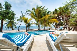 uma piscina com duas espreguiçadeiras e o oceano em Photo Perfect-Beachfront 2 Bedroom-Infinity Pool em Placencia Village